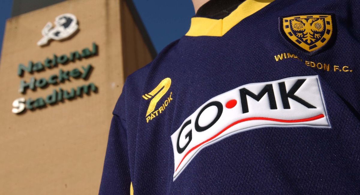 A close-up of a Wimbledon shirt on a fan, with the sponsor &#039;Go MK&#039;, following the club&#039;s controversial relocation to Milton Keynes in 2003