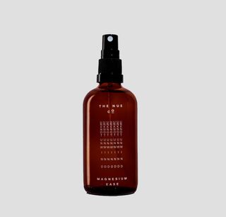 The Nue Co. magnesium spray in brown bottle against grey background