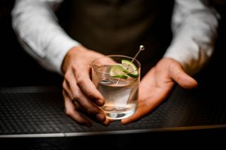 A bartender handing over a clear cocktail