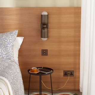 bedside table in front of wooden wall with industrial-style wall sconce