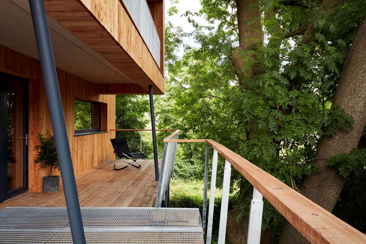 The balcony of the treehouse has wooden rails and overlooks the surrounding forest