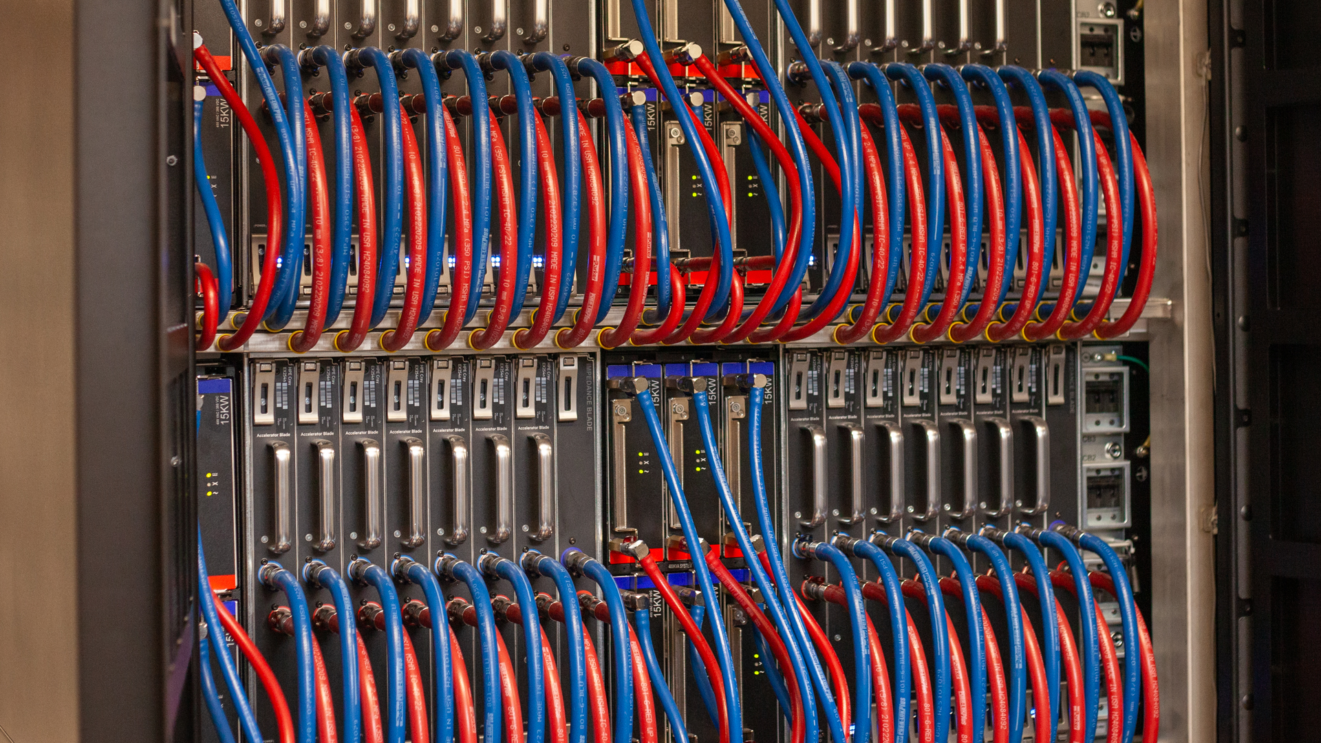 A close-up of the server cabinets within the Isambard-AI supercomputer, with 'blades' containing eight Nvidia GH200 Grace Hopper Superchips and covered in wires and cooling pipes.