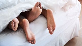 Feet poking out the end of the bed, lying together to signify couple intimacy