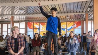 Jin Wang stands on a cafeteria table surrounded by his fellow students in American Born Chinese