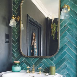 Bathroom with green herringbone tiles and gold mirror