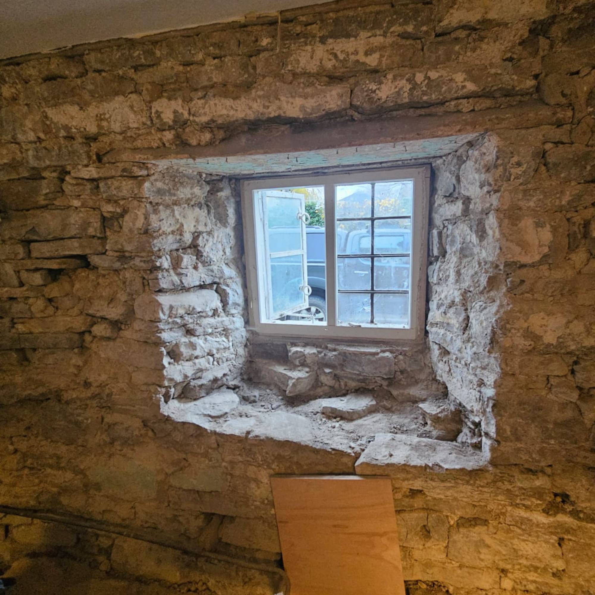 bare stone will with white wooden window