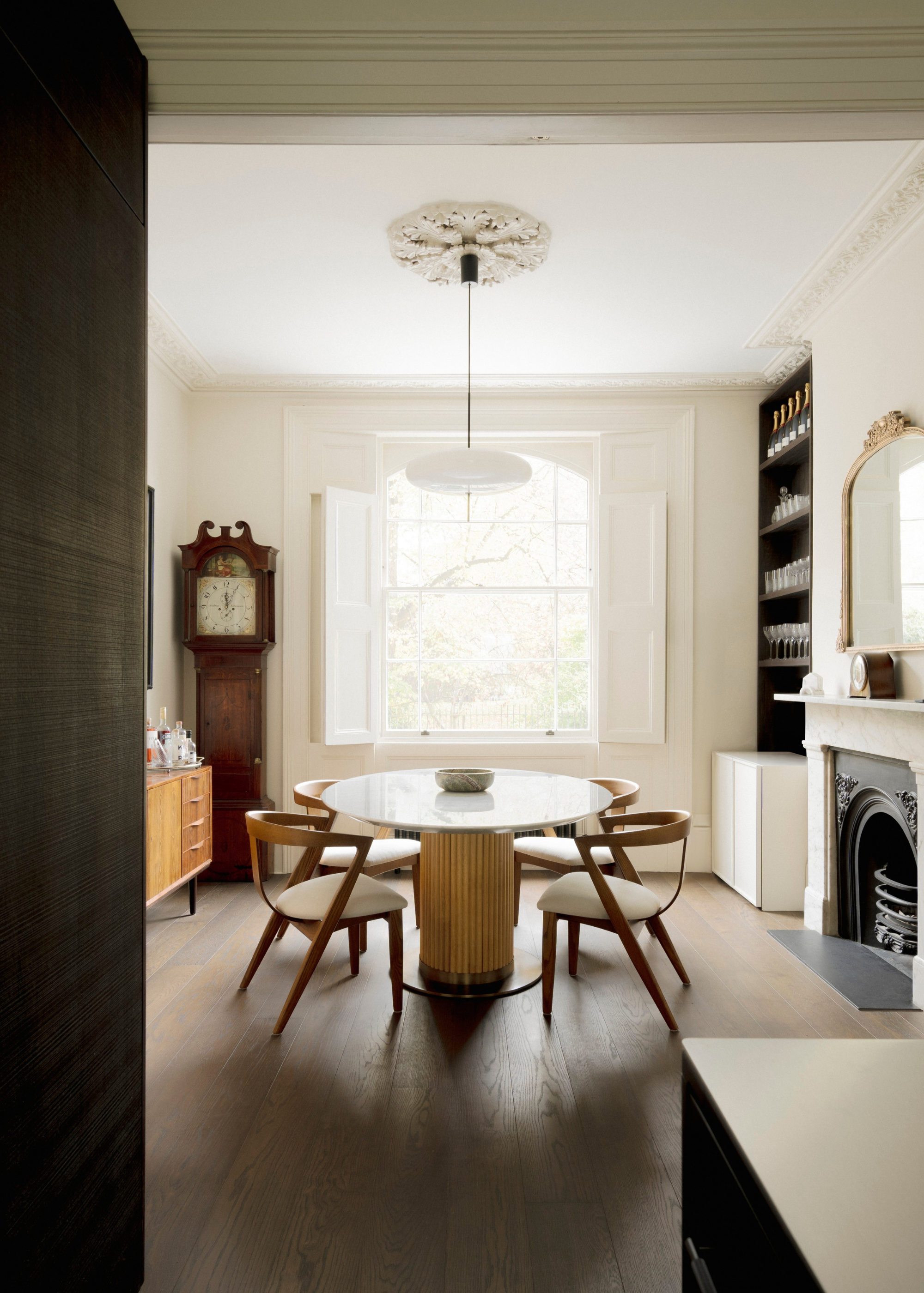 dark wooden flooring in a light-filled room with big windows and a small round dining table