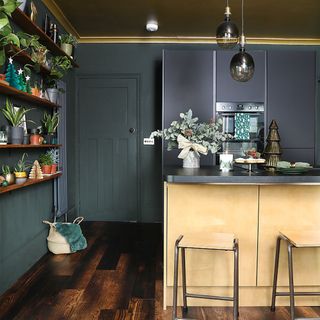 Black kitchen with gold island, bar stools and glass pendant lights