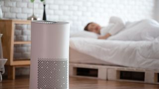 woman sleeping next to an air purifier in her bedroom