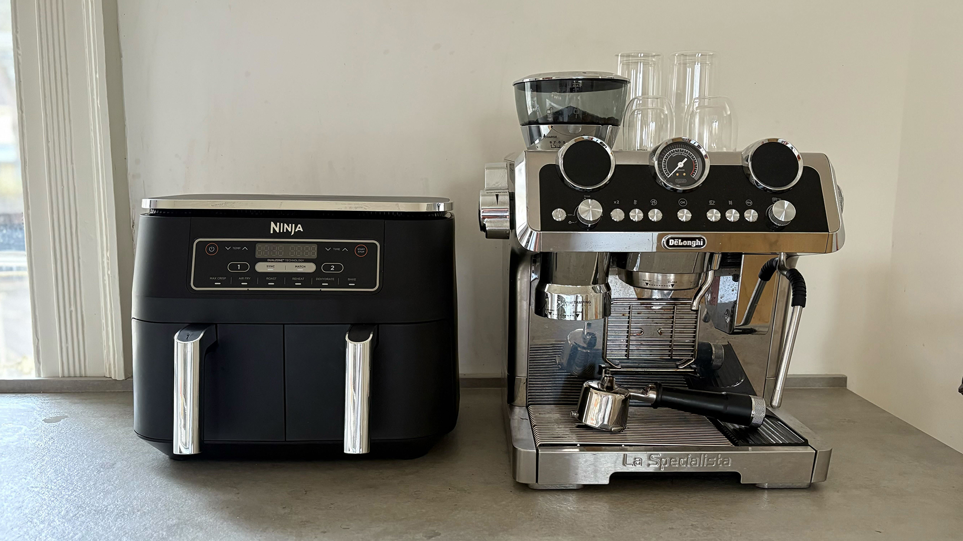 Ninja air fryer next to a stainless steel coffee machine on a kitchen countertop