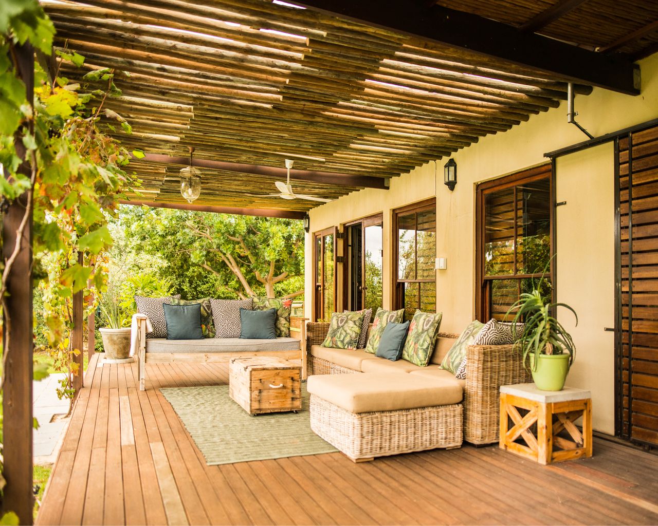 Wicker patio sofa and furniture sitting outside on a rustic wooden balcony on a sunny afternoon