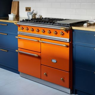 a dark blue kitchen and a bright orange range cooker