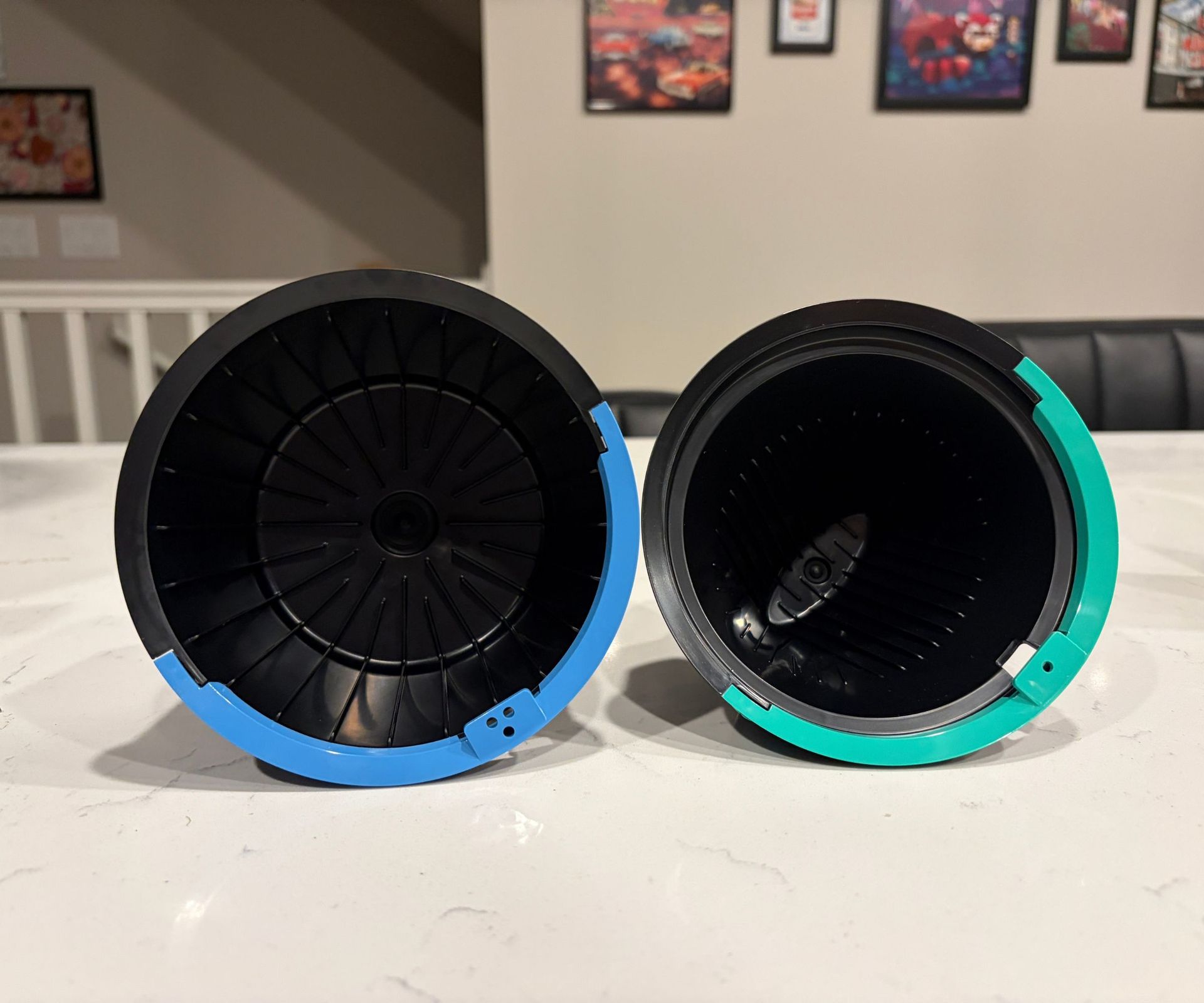 Two different sized filter baskets for a coffee maker on a white kitchen counter.
