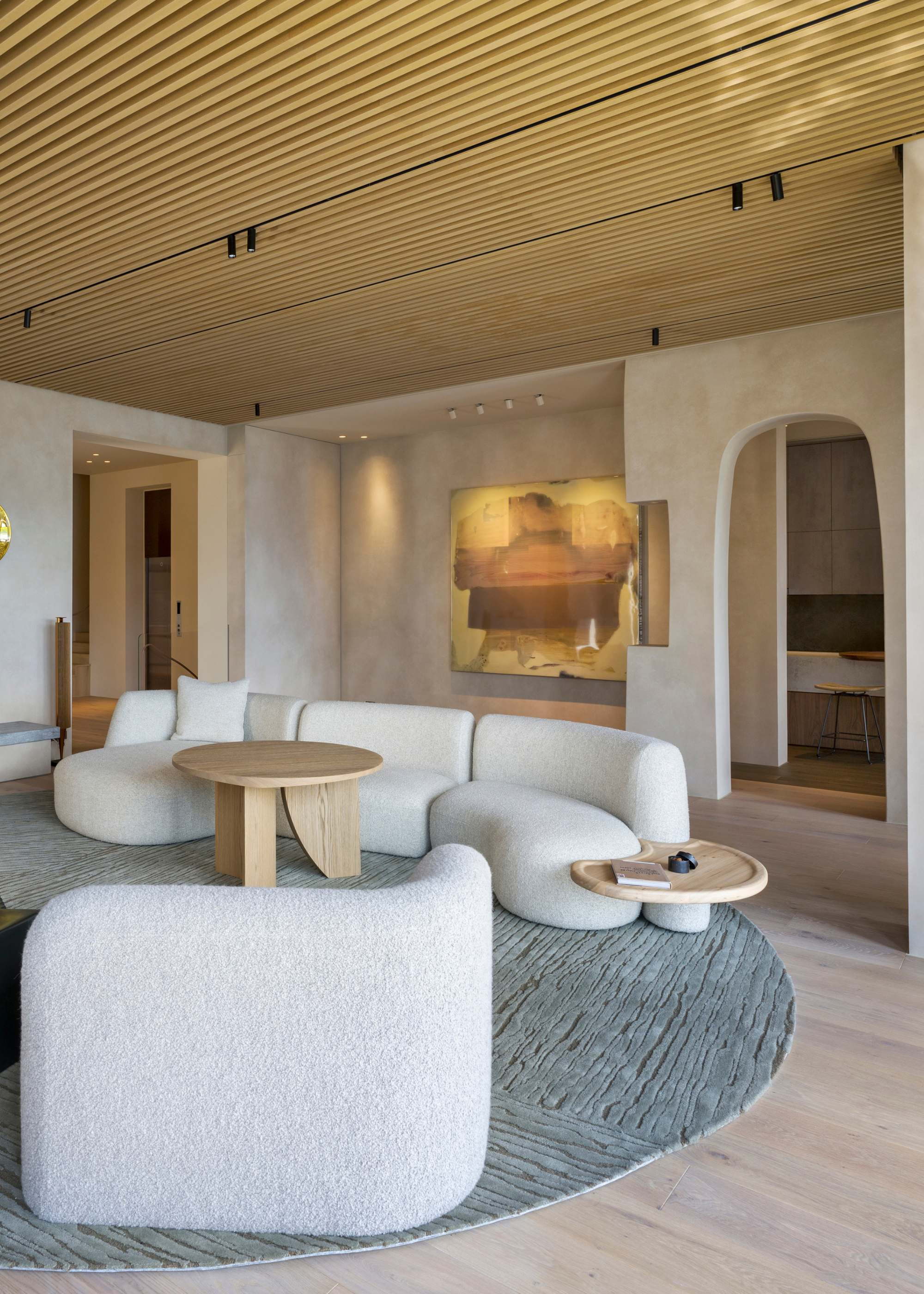 A bright living room with boucle white couches and round wood side tables on a circular rug