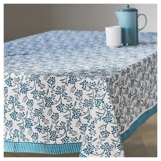 A rectangular tablecloth from Anthropologie with a blue floral design on a white backdrop