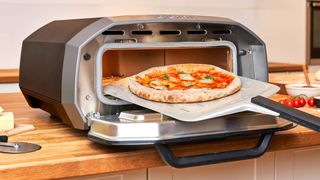 ooni volt pizza oven on a worksurface, having a pizza taken out of it