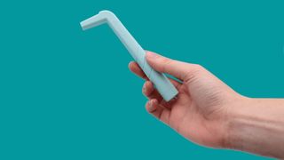 image of a hand holding the hiccup-relieving device, which resembles a big plastic straw with a mouth piece at the top
