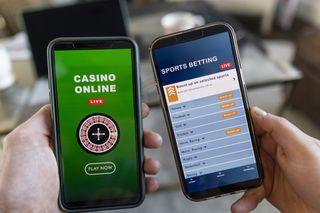 Man and woman holding smart phones in their hand and they are using them to gamble in an online casino and sports bet online.