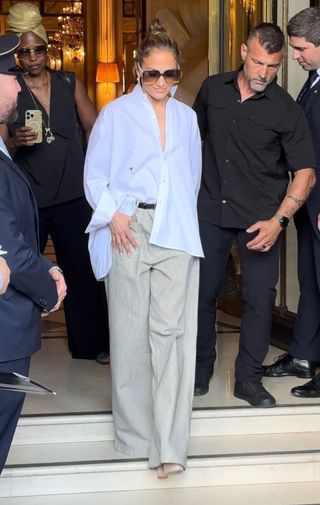 Jennifer Lopez wears a white button-down shirt with baggy trousers.