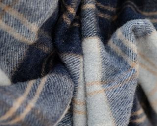 A navy, white and grey tartan blanket made from recycled fibres
