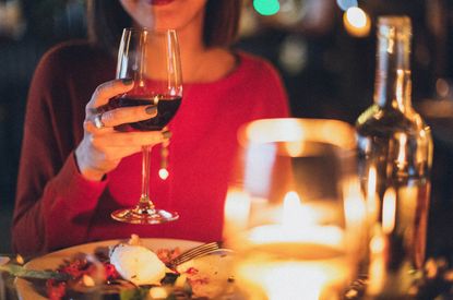 A woman at a dinner table holding a glass of red wine