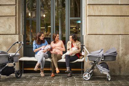 Expectant and friends with babies sitting on bench