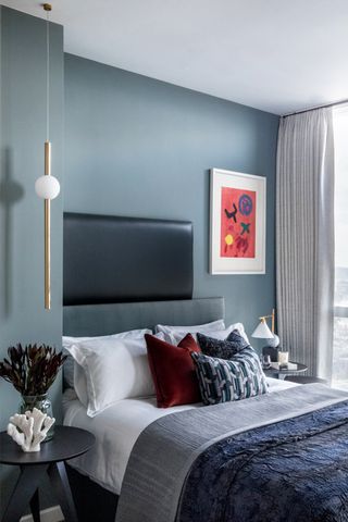 Blue bedroom with red artwork and cushions