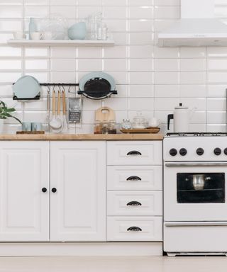 An image of a kitchen with wooden cabinet doors, wooden countertops and a white oven with off white subway tiling