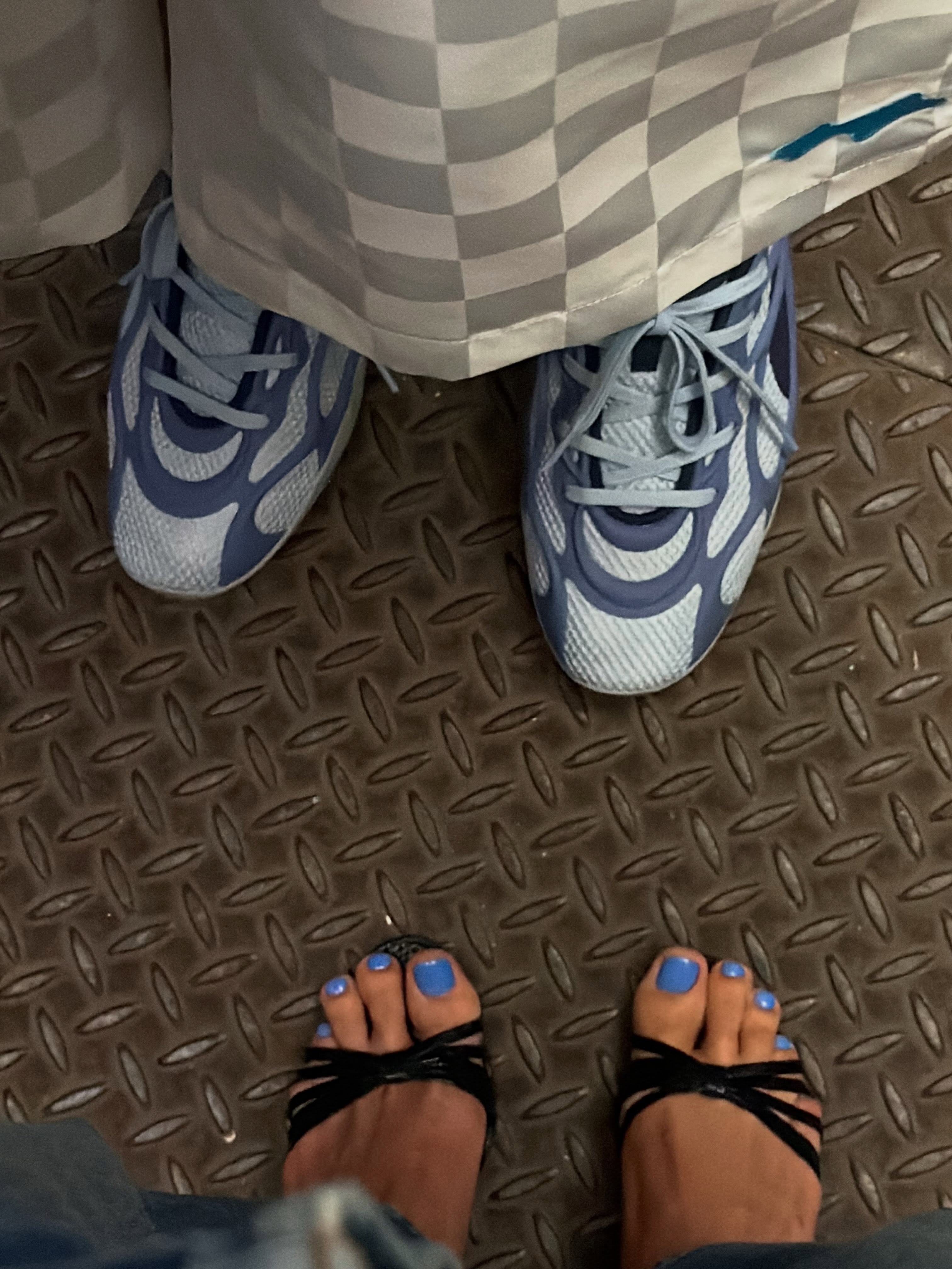 Hailey Bieber wearing black sandals with blue nail polish on her toes