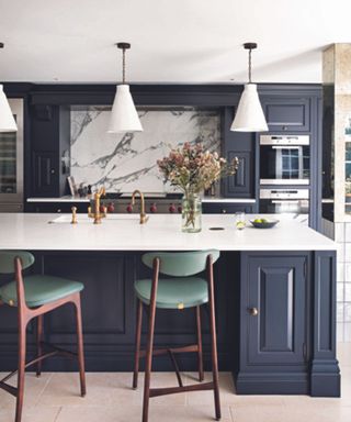A kitchen with dark blue cabinets and marble backsplash