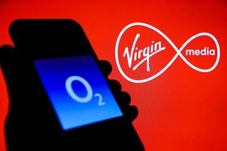 Virgin Media O2: O2 logo is seen displayed on a phone screen with Virgin Media logo displayed on the background