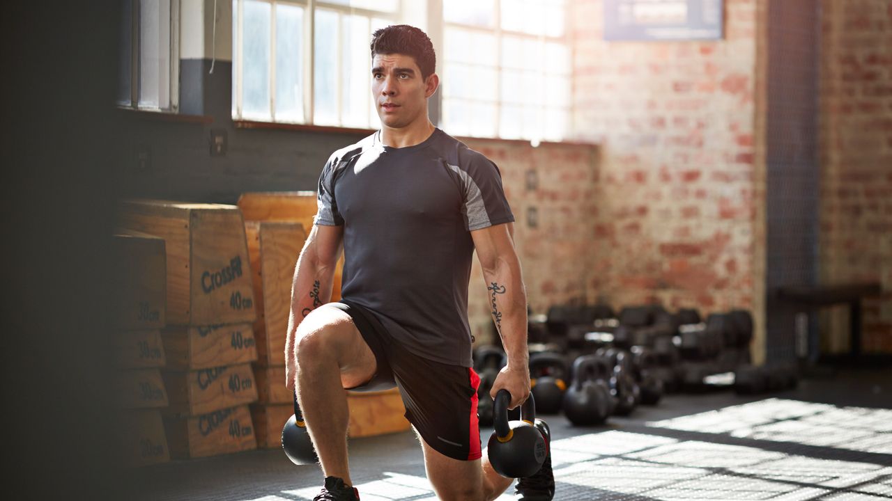 Man workouts with two kettlebells in either hand