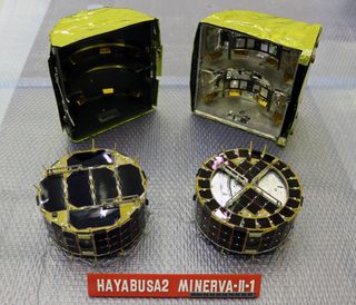 A close look at the Japan Aerospace Exploration Agency's MINERVA-II1 rovers delivered to asteroid Ryugu by the Hayabusa2 spacecraft in September 2018. Rover-1A is on the left, with Rover-1B on the right. In back is the cover in which they were stored.