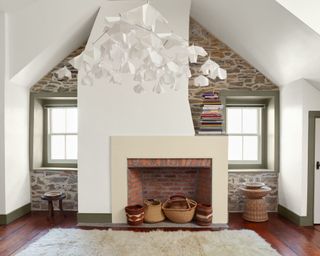 living room with dark wood floors, white walls with sloped ceiling, brick wall and sage green window trim and skirting