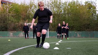 Woman doing football drills on pitch with friends