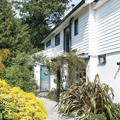 White house with wall panelling and mature garden