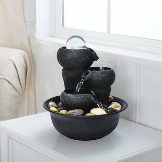 Small black iron water fountain on white shelf