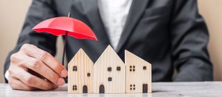 man in suit holding umbrella above wooden houses