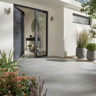 Grey concrete patio with planters and sliding french doors