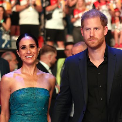 Meghan Markle wears a green strapless dress while Prince Harry wears a black suit with black shirt underneath