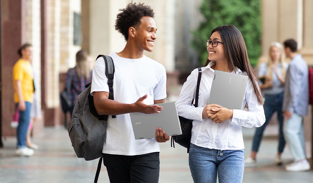 Students carry Acer Chromebooks while walking and chatting together 