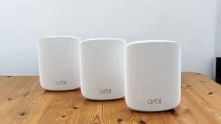 Netgear Orbi RBK353 on a wooden table in front of a white background