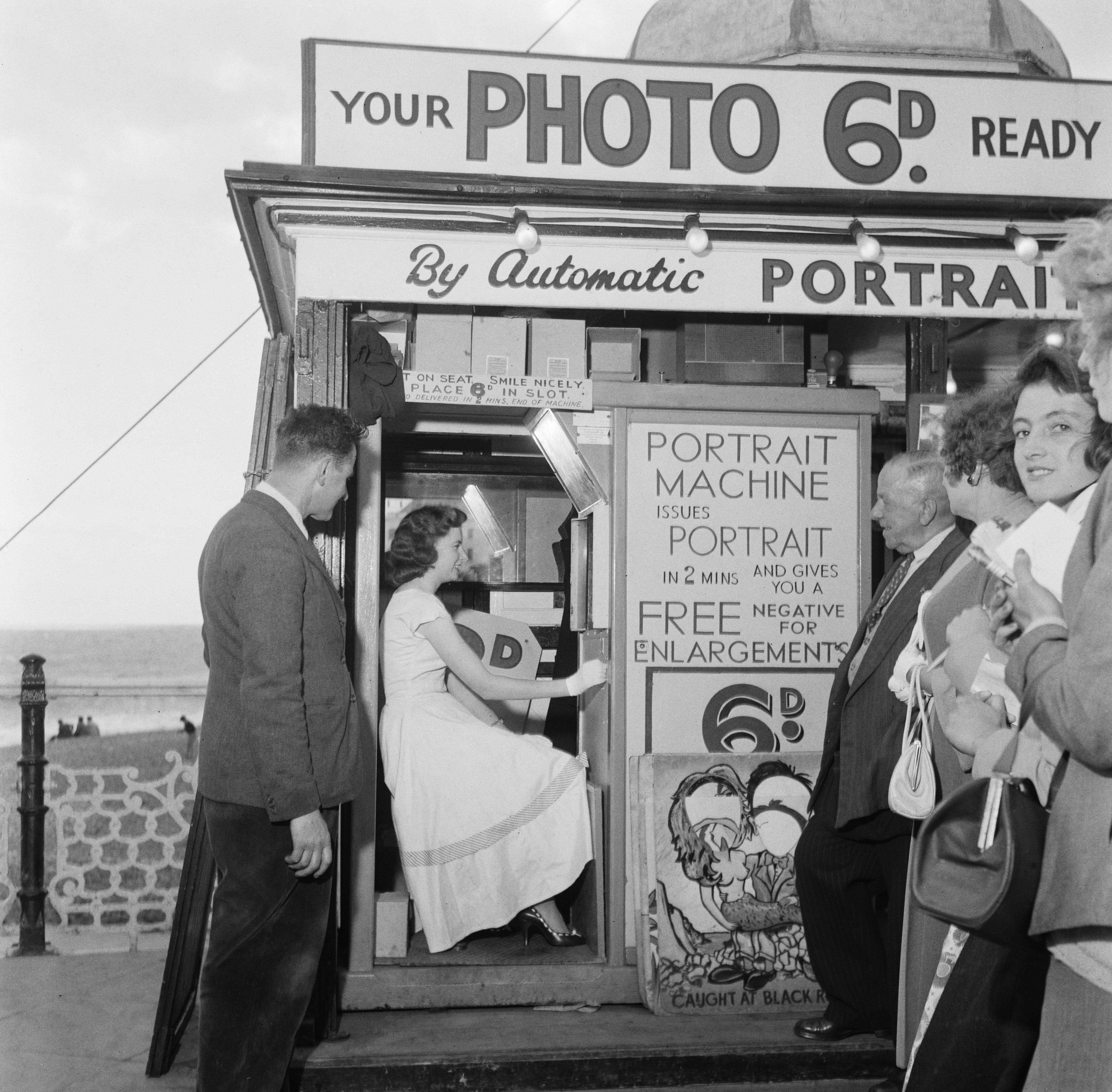 Ruby Murray is observed by a small group of admirers as she has her picture taken in a photo booth at Brighton Pier