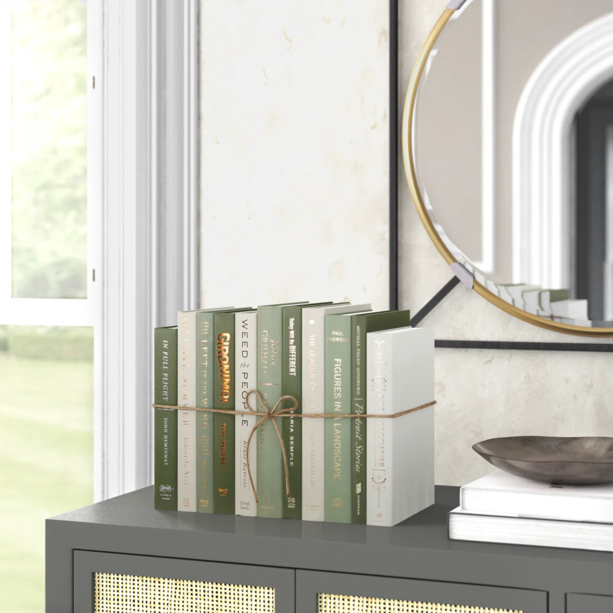 A set of sage green and white decorative books sitting on a gray console table