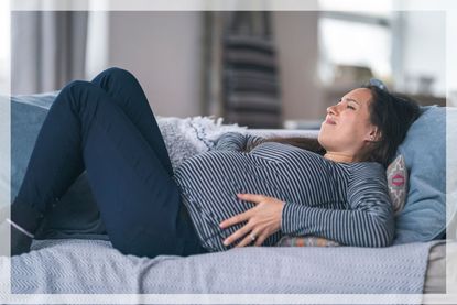 Pregnant woman laying down and holding her hips, as if suffering with pelvic pain during pregnancy