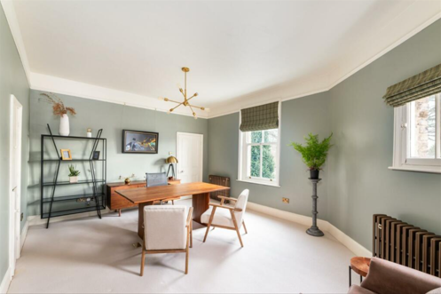 A lime green walled office with small wooden table