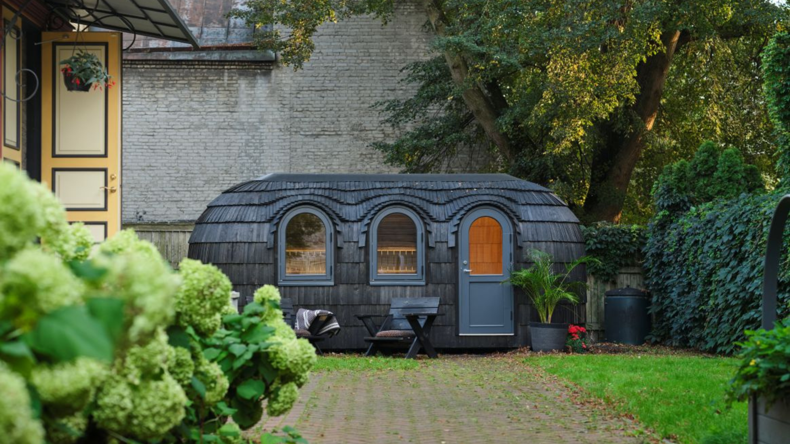 black, shingle sauna in a garden