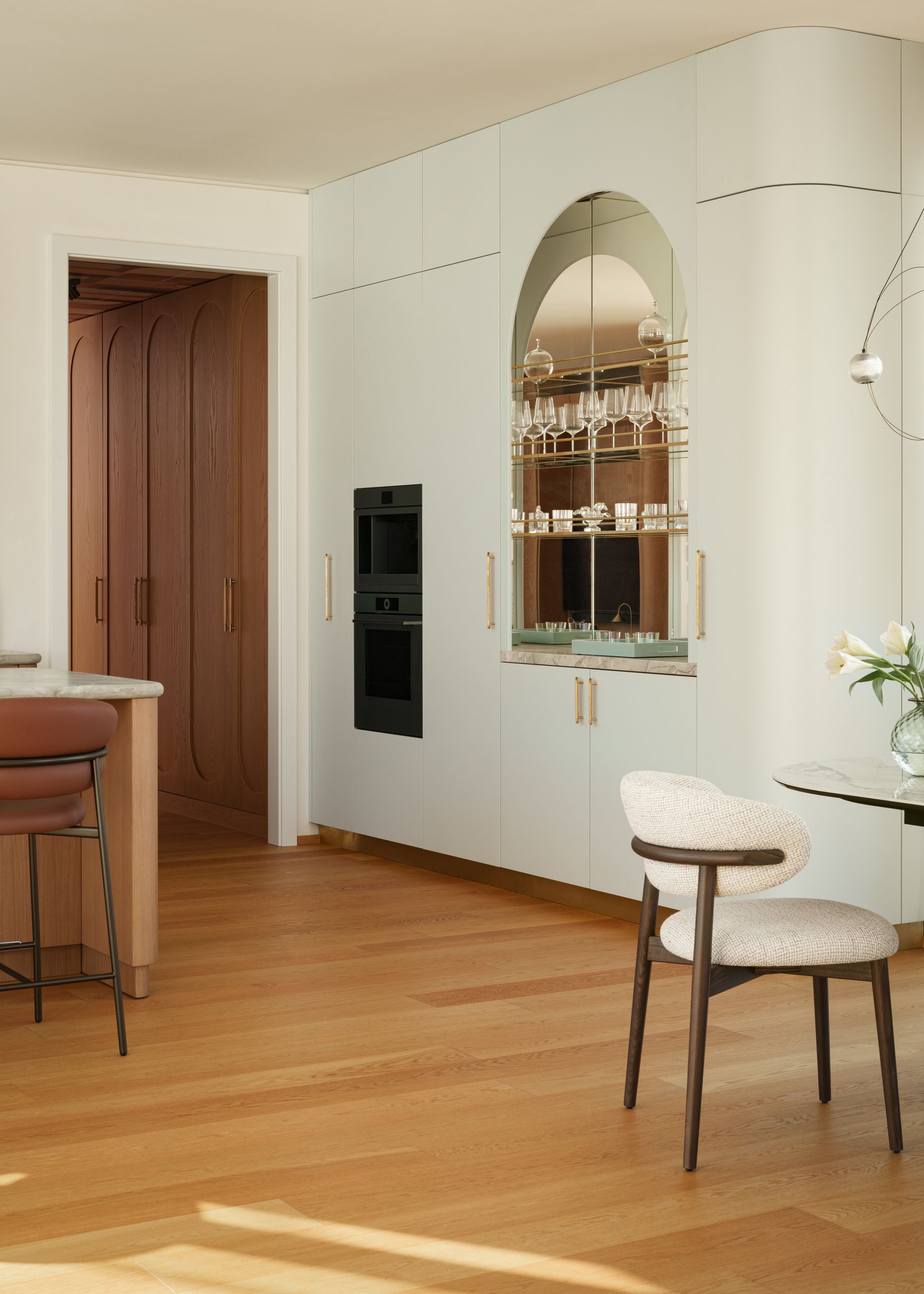 Image of an small open plan kitchen and dining area. There are wooden floors and white curved walls. 