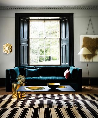 Living room pictures showing a green velvet sofa, monochrome rug and brass accessories.