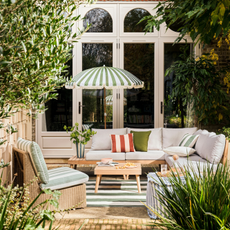 Habitat green striped Sunbeam parasol on a patio. There is a green striped garden accent chair, grey sofa set and wood coffee table.